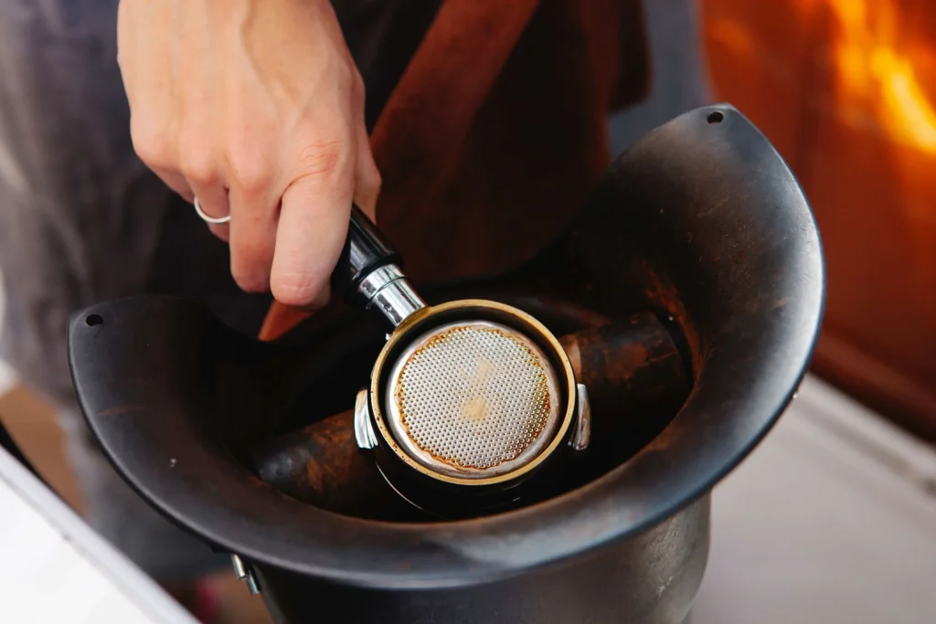 Barista purging 2g into knock box after grind change