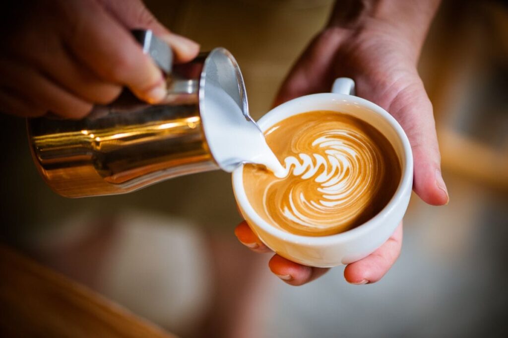 Barista pouring latte with creamy, blend-based espresso
